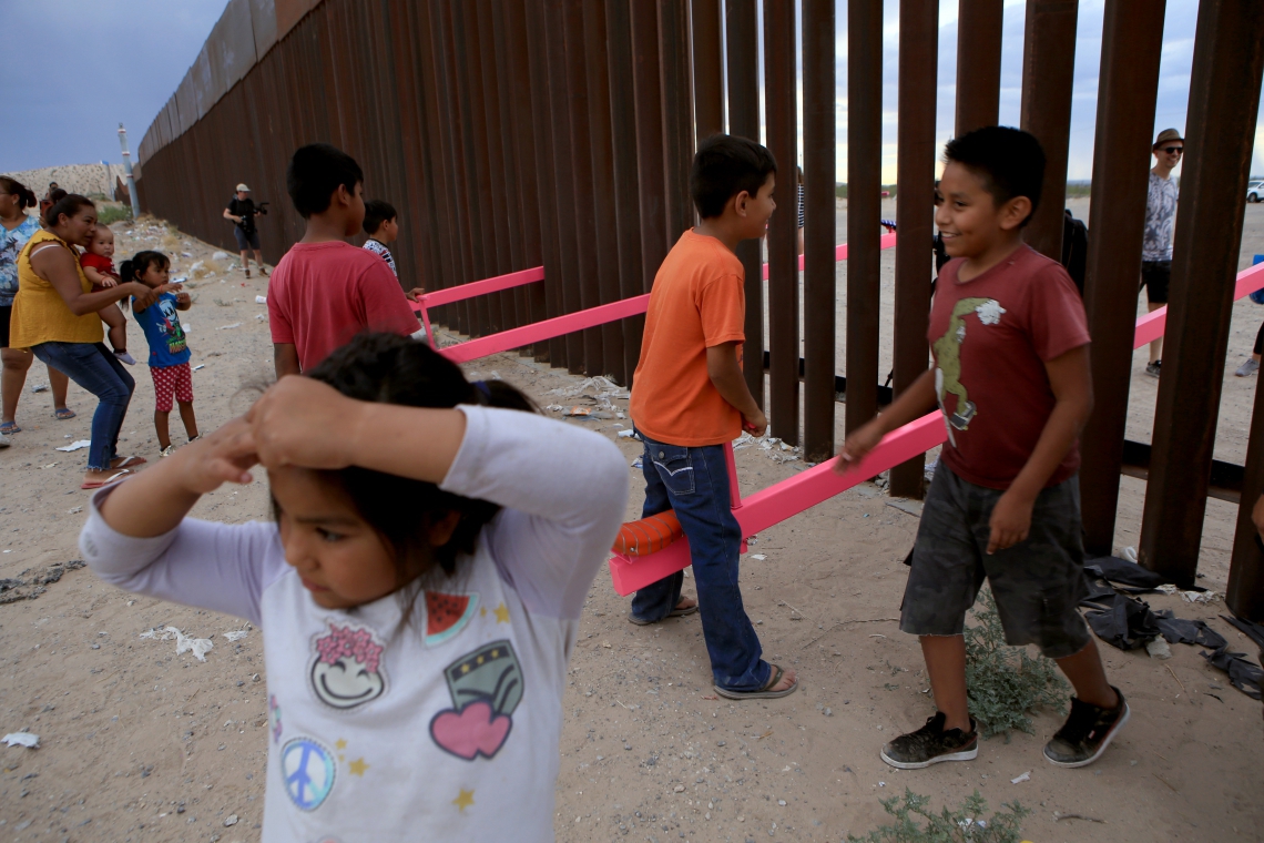 Crianças americanas e mexicanas brincam em gangorras instaladas na fronteira mexicana com os EUA (Foto: LUIS TORRES / AFP)
