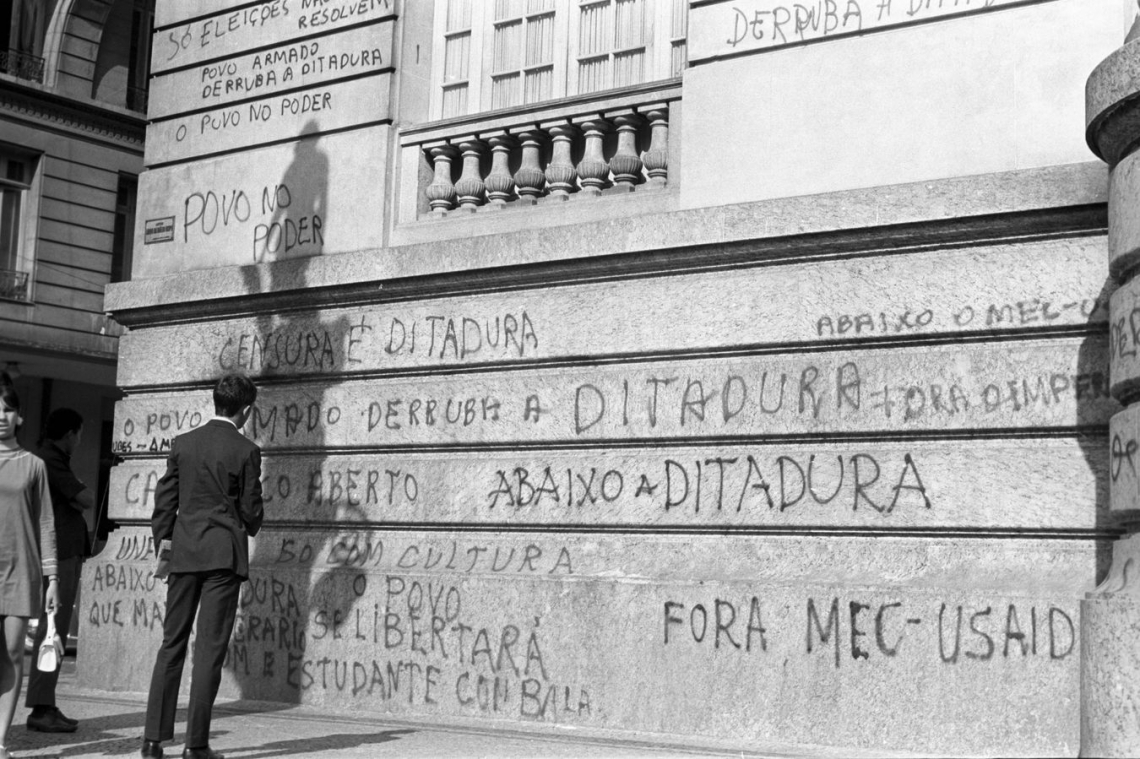 Em maios de 1968, homem lê a pixação de protesto na fachada do prédio