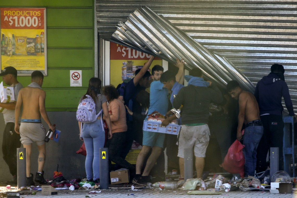 Pessoas saquearam um supermercado em Puente Alto, área metropolitana de Santiago, em 20 de outubro de 2019. - Novos confrontos eclodiram na capital do Chile, Santiago, no domingo, depois que duas pessoas morreram quando um supermercado foi incendiado durante a noite, enquanto protestos violentos provocavam raiva por condições econômicas e sociais. a desigualdade atingiu o terceiro dia. (Foto de Dragomir YANKOVIC / ATON CHILE / AFP) 