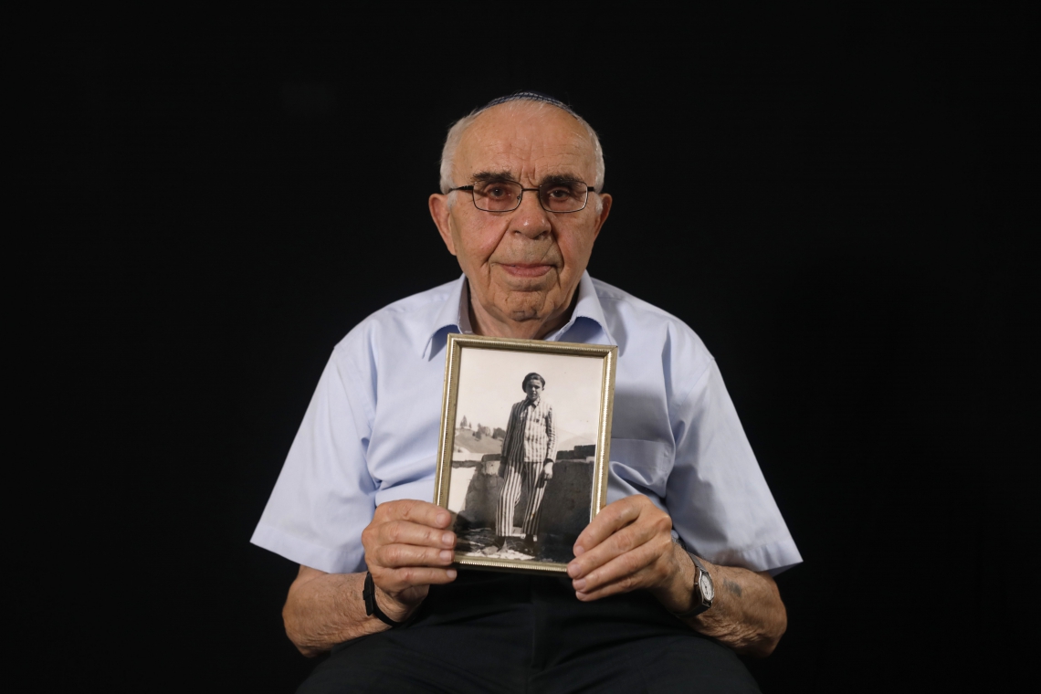 Menahem Haberman posa com uma foto sua depois da guerra(Foto: MENAHEM KAHANA/AFP)