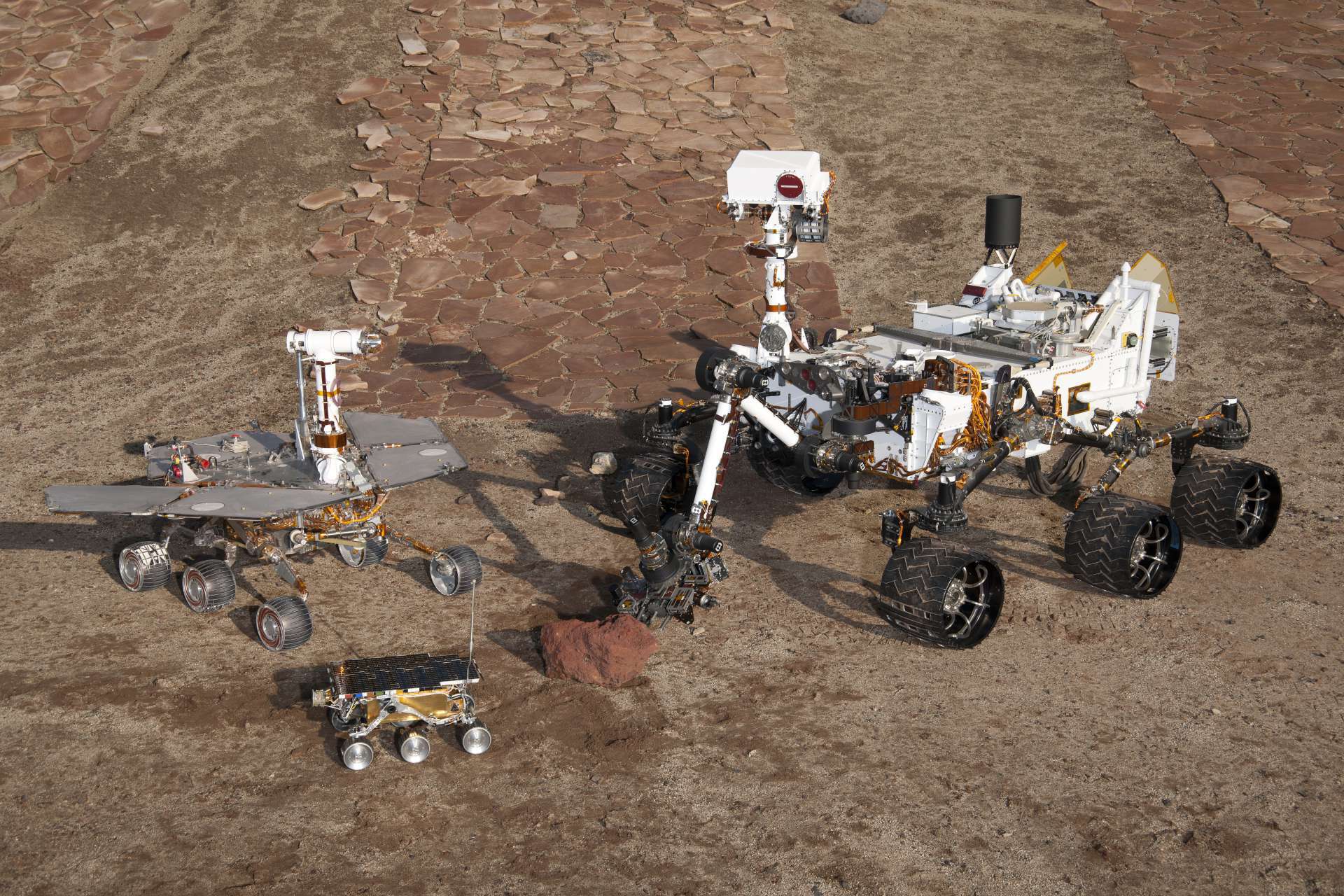 Três gerações de rovers de Martetodos da NASA: à frente e o centro peças sobressalentes do primeiro rover, Sojourner, que pousou em 1997. À esquerda, rover de teste irmão do Spirit and Opportunity, que aterrissou em 2004. À direita, rover de teste do tamanho do Curiosity(Foto: NASA/JPL-Caltech)