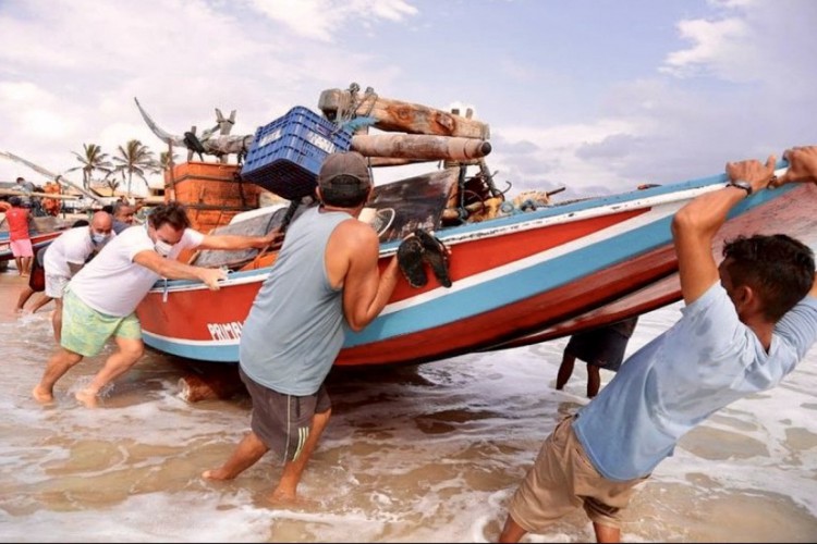Presidente da Caixa incluiu pesca em alto mar com associação de Cascavel. Na foto, de camisa branca, retirando a jangada do mar. 