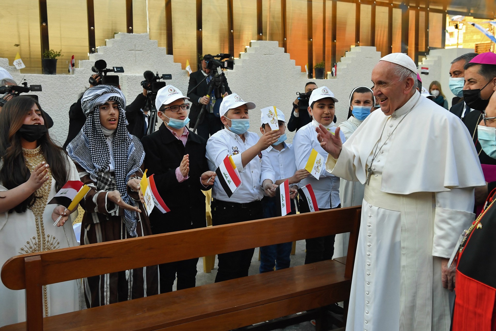 Uma imagem divulgada pelo escritório de mídia do Vaticano em 6 de março de 2021 mostra o Papa Francisco (R) saudado por crianças em sua chegada para uma missa na Catedral de São José de Bagdá no segundo dia da primeira visita papal ao Iraque. - A visita do pontífice de 5 a 8 de março, a primeira de um papa ao Iraque, inclui orações inter-religiosas na antiga cidade de Ur, onde a Bíblia diz que Abraão, o pai de três religiões, judaísmo, cristianismo e islamismo, nasceu. e é um dos locais mais antigos da Mesopotâmia. (Foto por - / VATICAN MEDIA / AFP) /