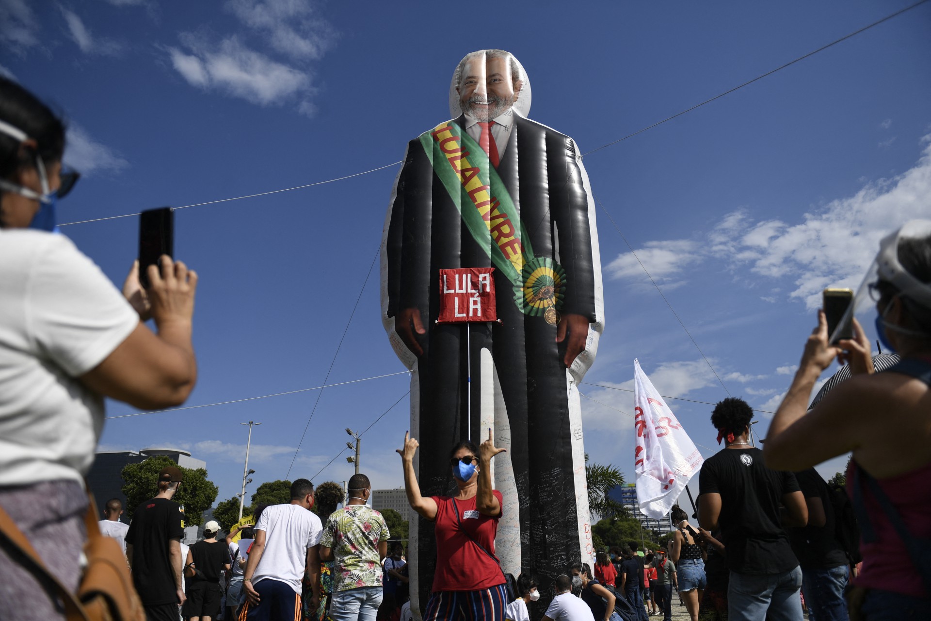 Uma mulher posa para uma foto com um manequim retratando o ex-presidente brasileiro (2003-2011) Luiz Inácio Lula da Silva com uma faixa lendo Lula Livre durante um protesto contra a forma como o presidente Jair Bolsonaro lidou com a pandemia de COVID-19 no centro do Rio de Janeiro, Brasil em 29 de maio de 2021. (Foto: MAURO PIMENTEL / AFP)