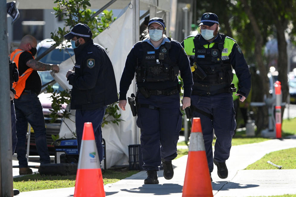 A polícia caminha do lado de fora de um prédio residencial no subúrbio de Campbelltown, no sudoeste de Sydney, em 4 de agosto de 2021, depois que os residentes foram colocados em isolamento devido a relatos de infecções por Covid-19 dentro do prédio