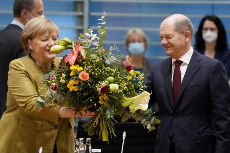 A chanceler alemã, Angela Merkel (E) recebe um buquê de flores do ministro das finanças alemão, vice-chanceler e candidato dos social-democratas (SPD) ao chanceler Olaf Scholz antes da reunião de gabinete na Chancelaria em Berlim, Alemanha, em 24 de novembro de 2021(Foto: MARKUS SCHREIBER / POOL / AFP)