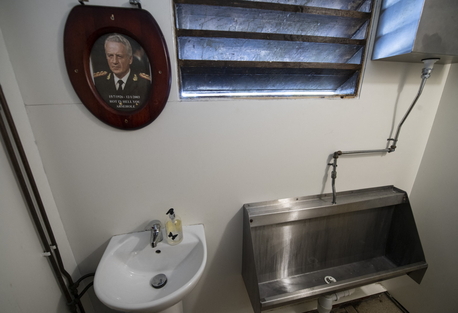 Esta foto de arquivo tirada em 17 de outubro de 2019 mostra um retrato do ditador argentino Leopoldo Galtieri (que liderou o ataque às Malvinas) emoldurada em uma tampa de sanitário, pendurada no banheiro do Victory Pub em Stanley, Ilhas Malvinas(Foto: PABLO PORCIUNCULA BRUNE / AFP)
