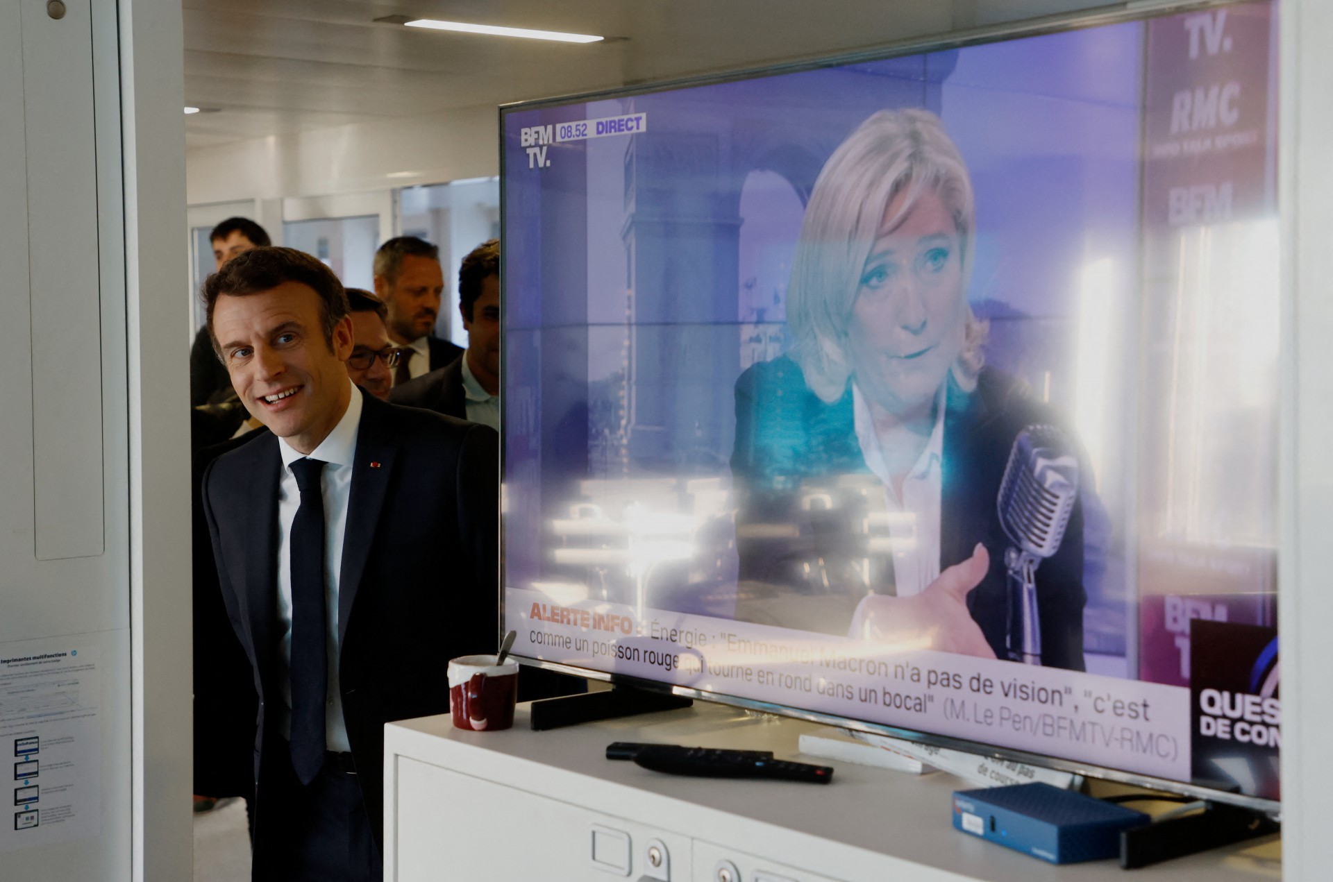 Nesta foto de arquivo tirada em 4 de abril de 2022, o presidente francês e líder do partido La Republique en Marche (LREM) Emmanuel Macron visita o escritório do Inter da França, ao lado de uma tela de TV exibindo o partido de extrema-direita francês Rassemblement National (RN) a candidata presidencial Marine Le Pen (D)(Foto: LUDOVIC MARIN / AFP)