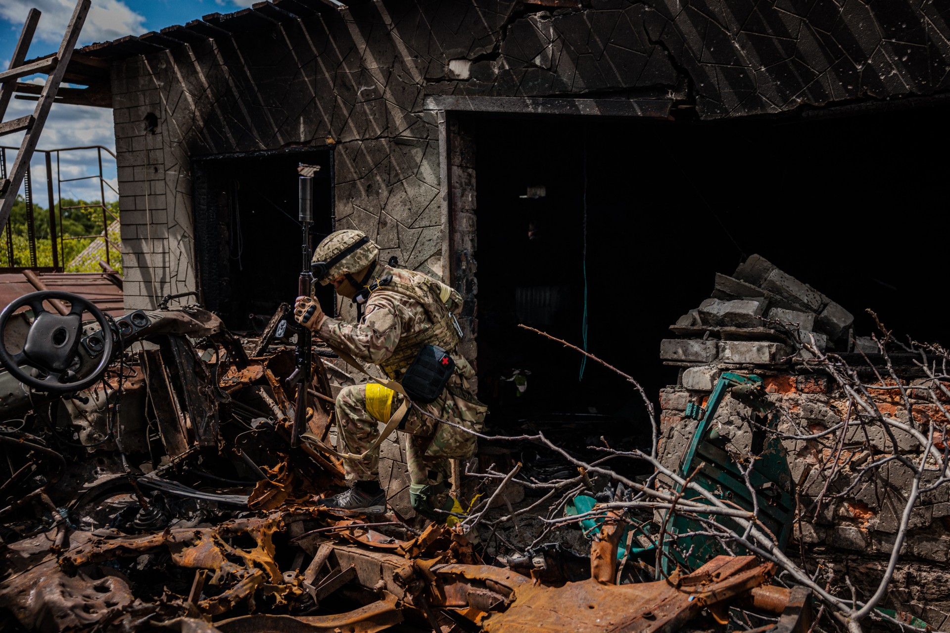 Um soldado da unidade de forças especiais ucranianas Kraken passa por destroços na vila de Rus'ka Lozova, ao norte de Kharkiv, em 16 de maio de 2022 (Foto: Dimitar DILKOFF / AFP)