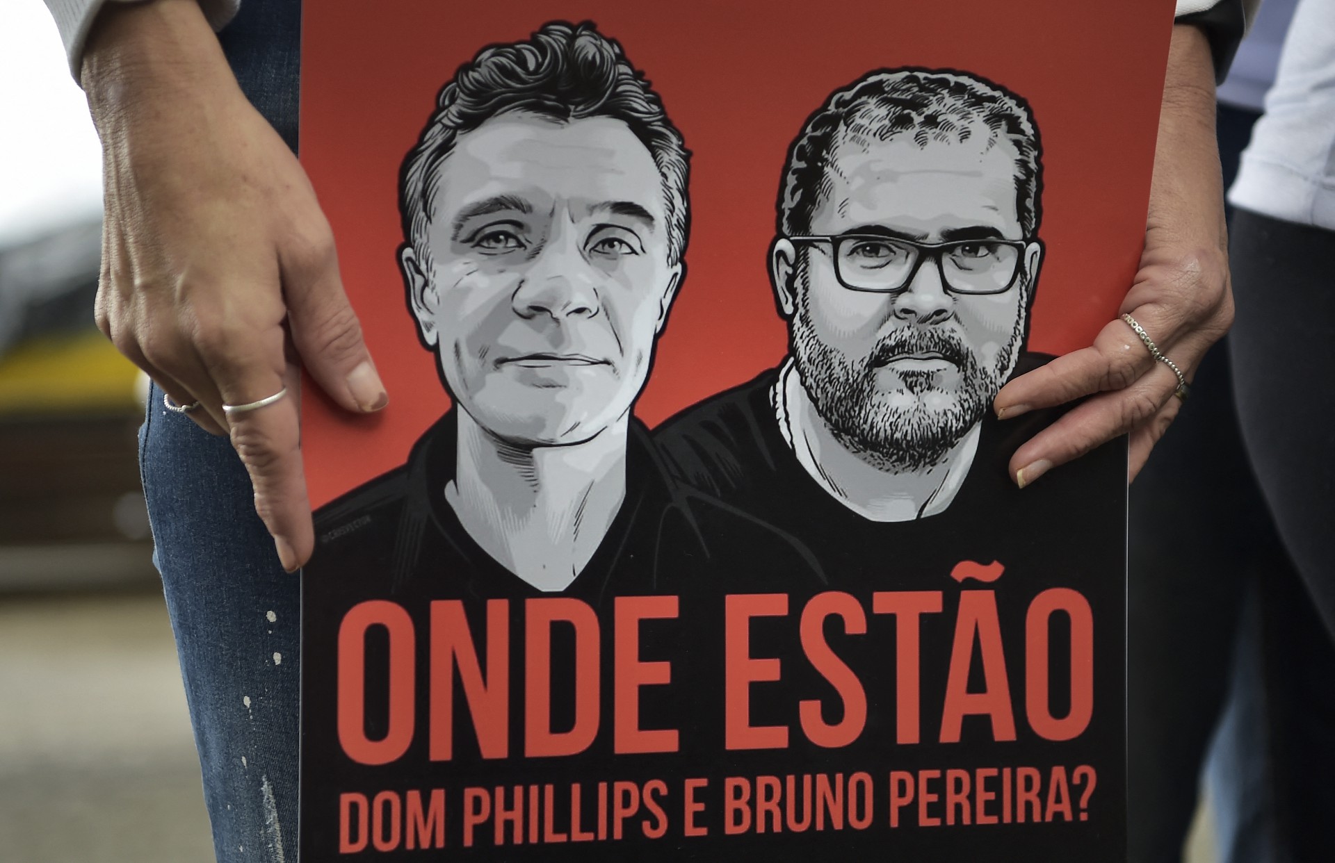 Um manifestante segura uma faixa com o jornalista britânico desaparecido Dom Philipps e o especialista indígena brasileiro Bruno Pereira lendo 