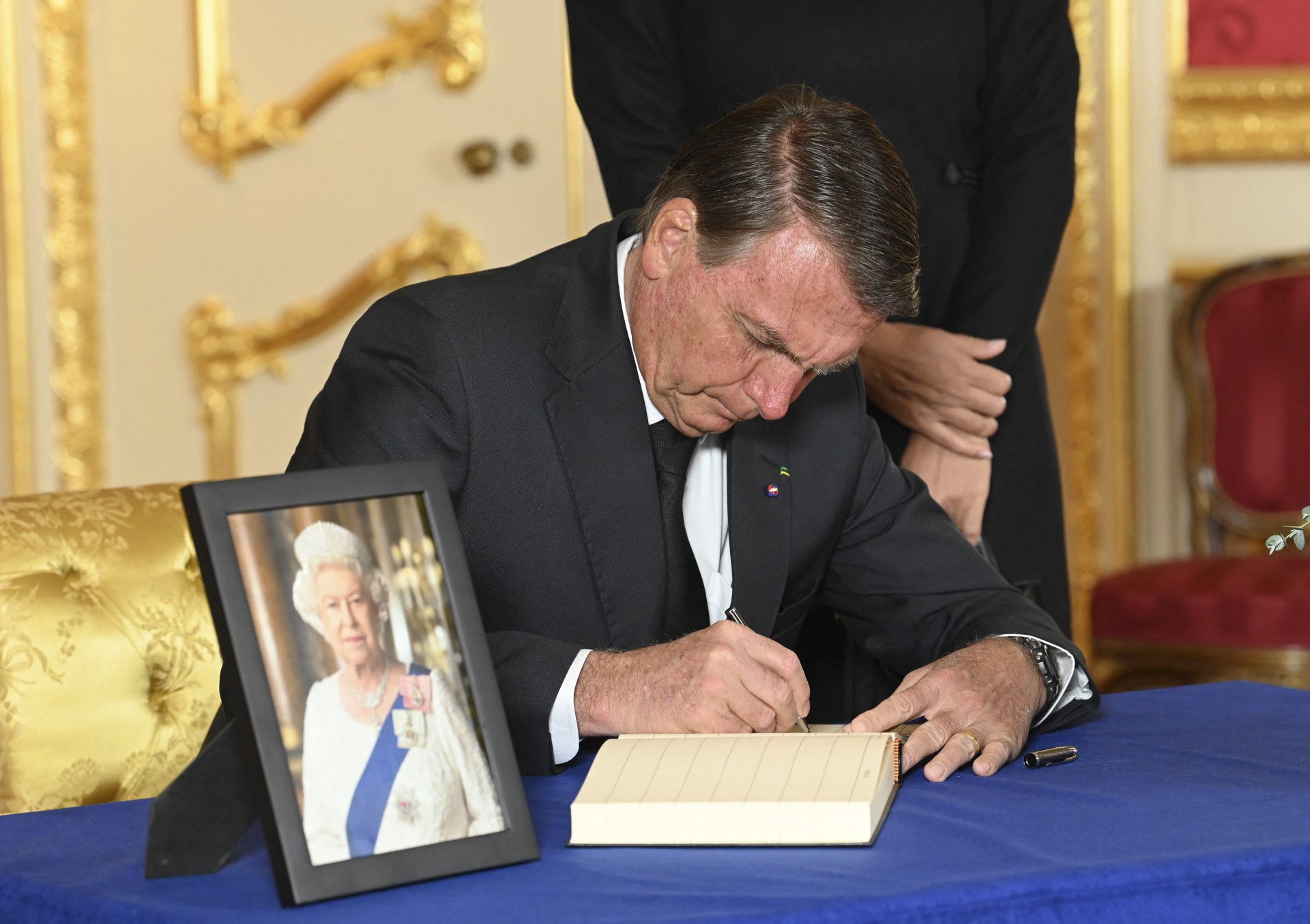 O presidente brasileiro Jair Bolsonaro assina um livro de condolências na Lancaster House, em Londres, em 18 de setembro de 2022, após a morte da rainha Elizabeth II em 8 de setembro(Foto: JONATHAN HORDLE / POOL / AFP)