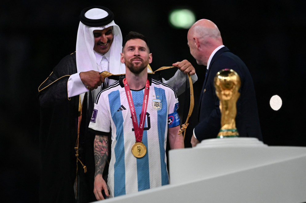 ￼ O EMIR Sheikh Tamim bin Hamad al-Thani envolve um bisht em torno de Messi(Foto: PAUL ELLIS / AFP)
