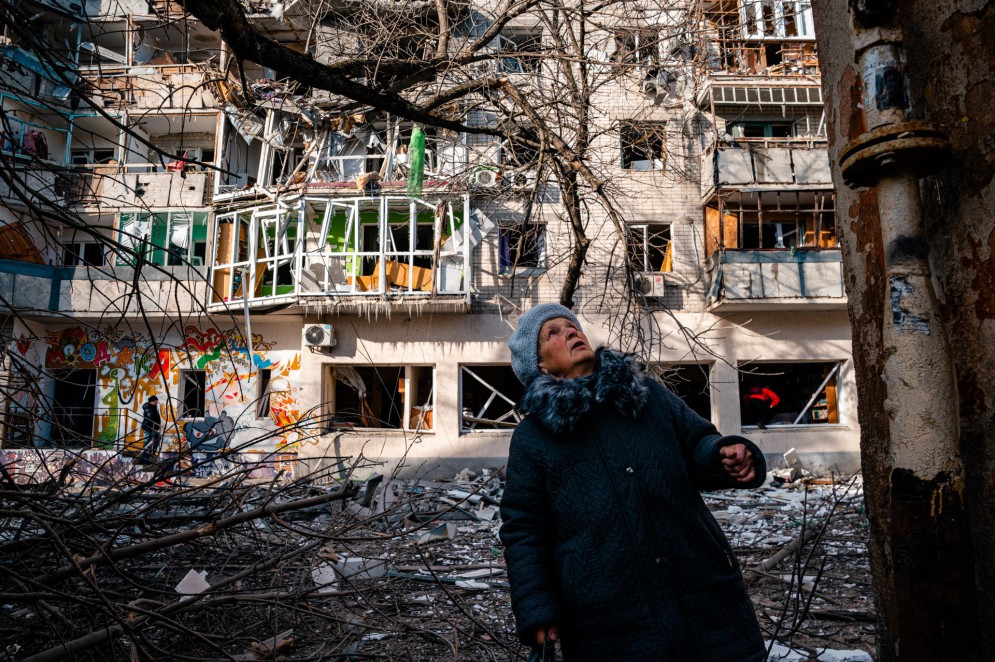 Uma senhora idosa observa em frente a um prédio residencial danificado pelo bombardeio russo em Kherson em 20 de dezembro de 2022, em meio à invasão russa da Ucrânia.(Foto: DIMITAR DILKOFF / AFP)