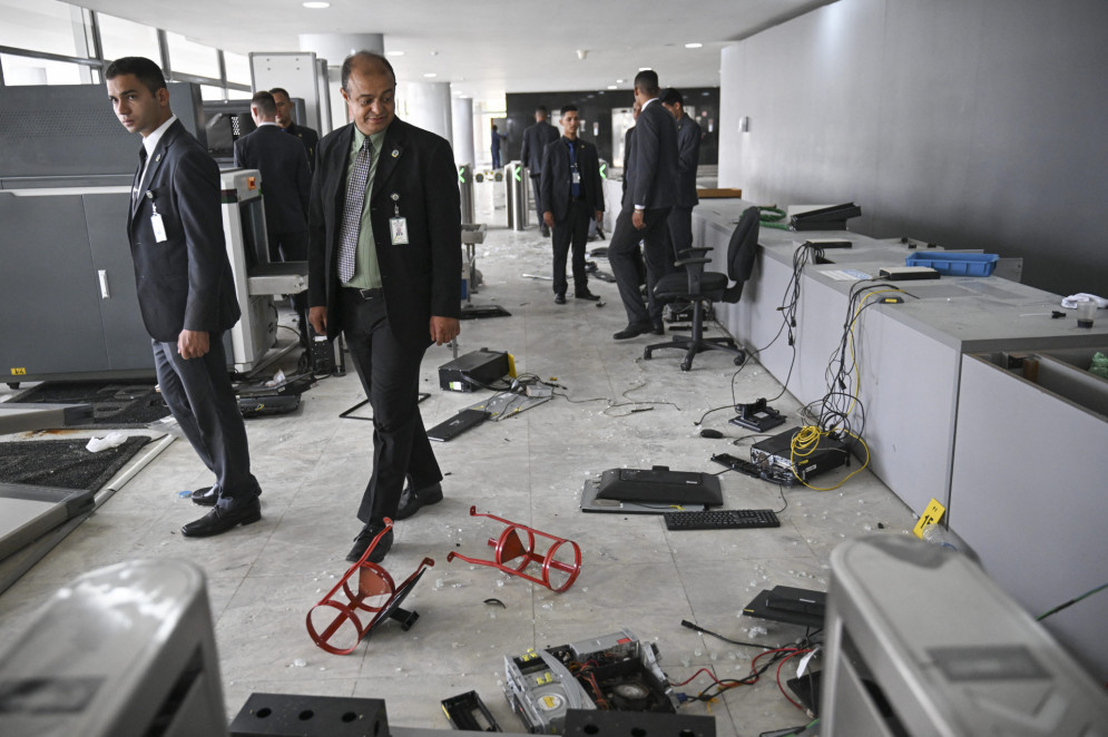 Membros da segurança do Palácio do Planalto caminham ao longo de uma das entradas do prédio destruído por apoiadores do ex-presidente brasileiro Jair Bolsonaro durante uma invasão em Brasília em 9 de janeiro de 2023(Foto: CARL DE SOUZA / AFP)