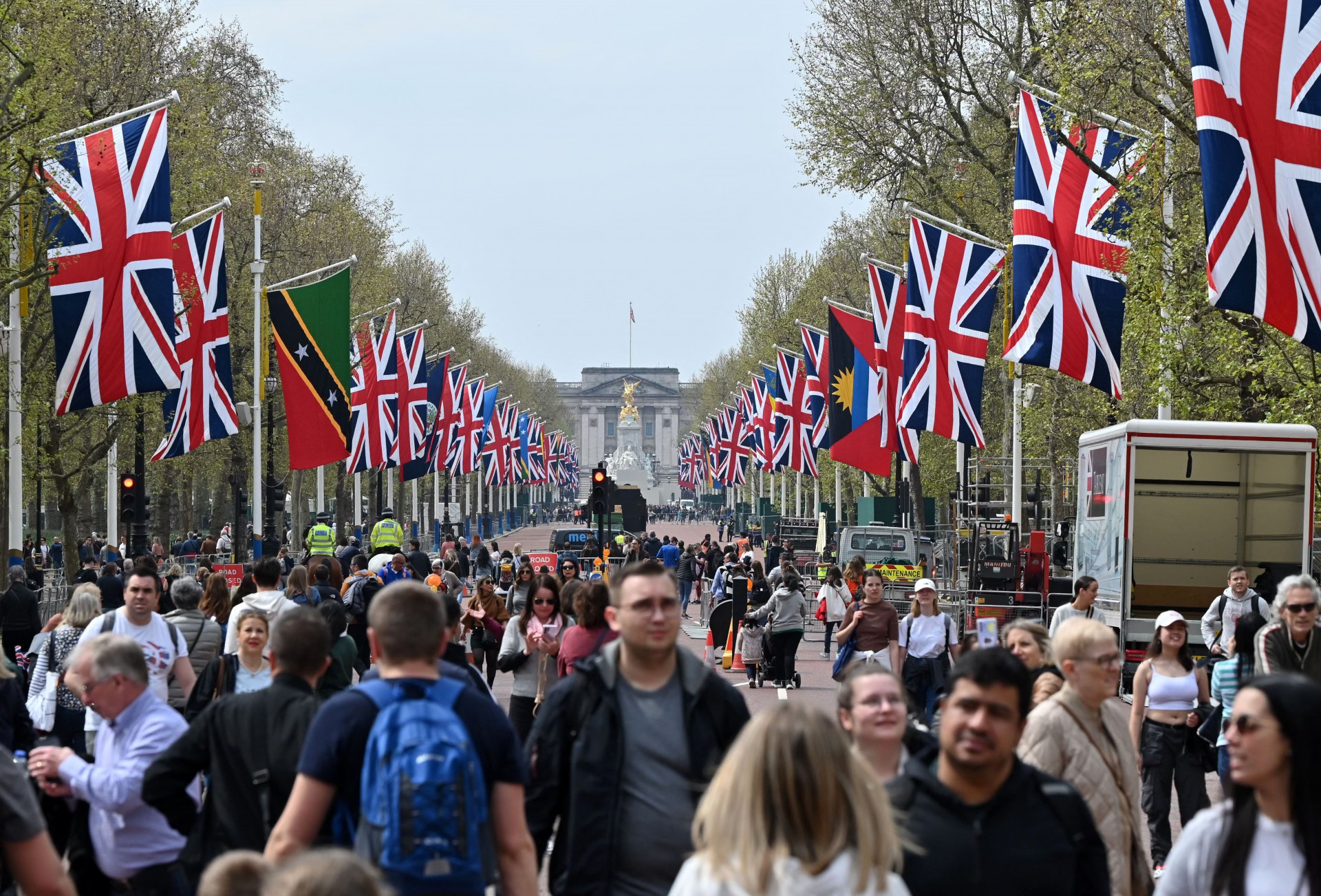 Pessoas caminham sob as bandeiras da União e da Commonwealth ao longo do The Mall, em direção ao Palácio de Buckingham, no centro de Londres, em 30 de abril de 2023(Foto: JUSTIN TALLIS / AFP)