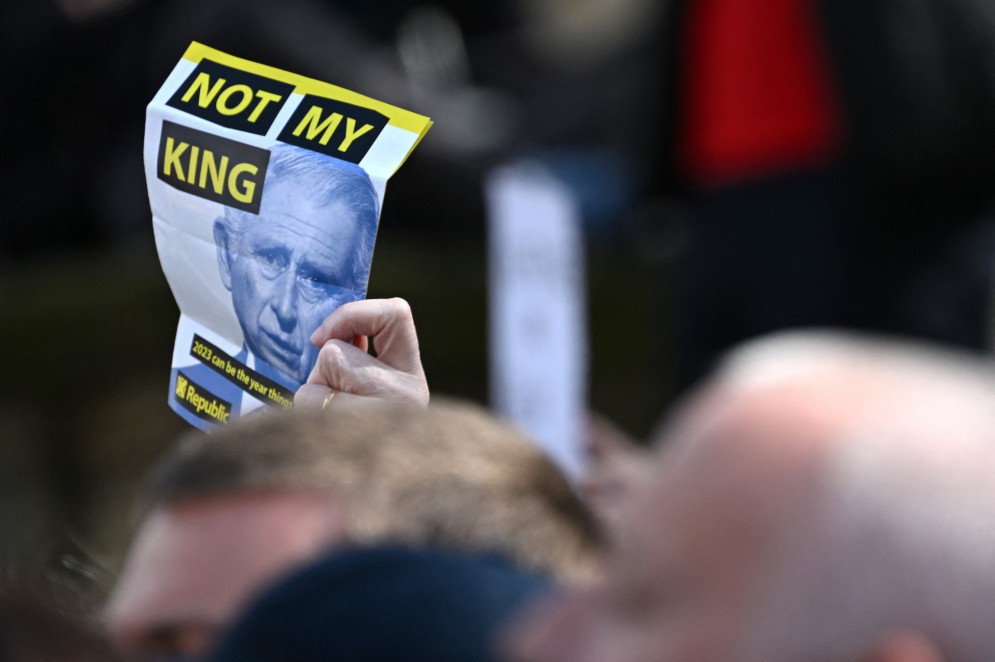 Os manifestantes seguram um panfleto com os dizeres "Not My King" antes da chegada do rei Charles III da Grã-Bretanha e da rainha consorte Camilla da Grã-Bretanha para uma visita à Biblioteca Central de Liverpool em 26 de abril de 2023(Foto: PAUL ELLIS / AFP)