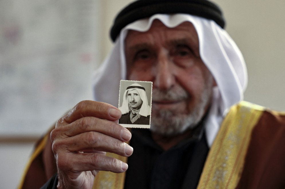 Nesta foto tirada em 3 de abril de 2023, o refugiado palestino Hassan al-Kilani apresenta uma fotografia sua quando jovem durante uma entrevista em sua casa, na cidade de Gaza(Foto: MOHAMMED ABED / AFP)