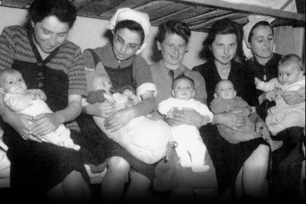 Mães carregam seus filhos nascidos no campo de concentração de Dachau. George Legmann é o primeiro bebê da direita para a esquerda.    (Foto: Acervo Museu do Holocausto/Reprodução)