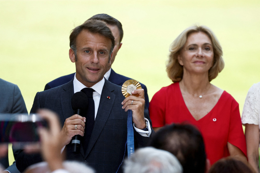 O presidente da França, Emmanuel Macron (E), segura uma medalha de ouro olímpica durante uma reunião com representantes de partes interessadas que contribuíram para a organização e realização dos Jogos Olímpicos de Paris de 2024, no Palácio Presidencial do Eliseu, em Paris, em 12 de agosto de 2024(Foto: Benoit Tessier / POOL / AFP)