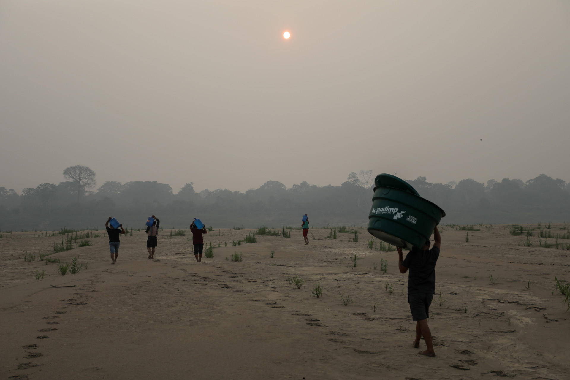 Moradores da comunidade Paraizinho carregam garrafões de água potável pelo leito do Rio Madeira em Humaitá, município do Amazonas. (Foto: MICHAEL DANTAS / AFP)