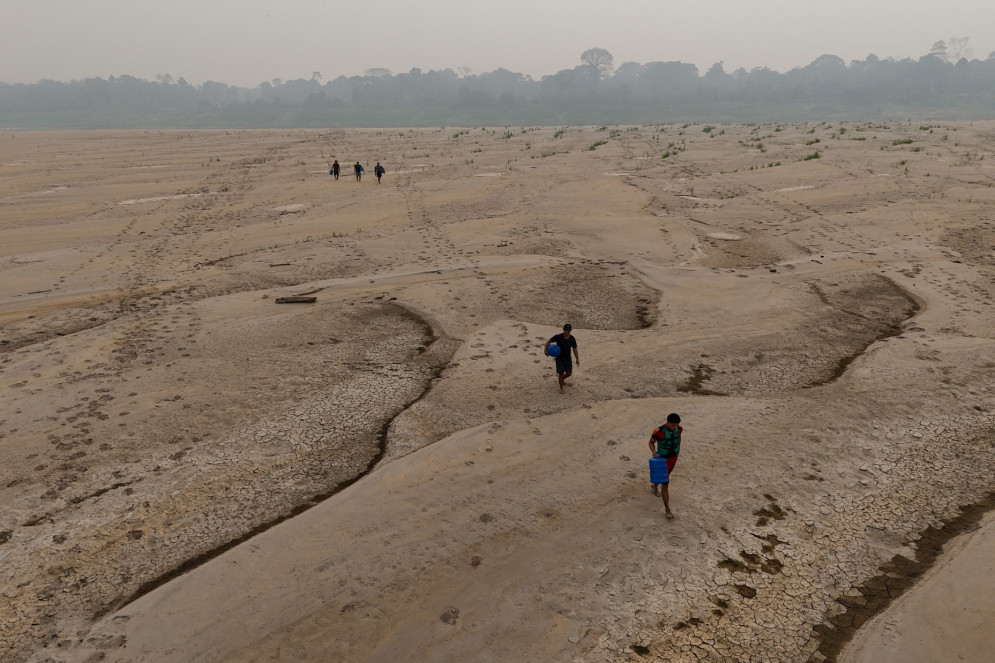 Moradores da comunidade Paraizinho carregam garrafões de água potável pelo leito do Rio Madeira em Humaitá, município do Amazonas.(Foto: MICHAEL DANTAS / AFP)