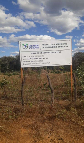 ParaTodosVerem: imagem exibe uma placa de licença estadual para a empresa Nova Agro Agropecuária, em Tabuleiro do Norte. A placa é branca e está fincada em uma vegetação de caatinga(Foto: Cecília Paiva/Escritório Frei Tito)