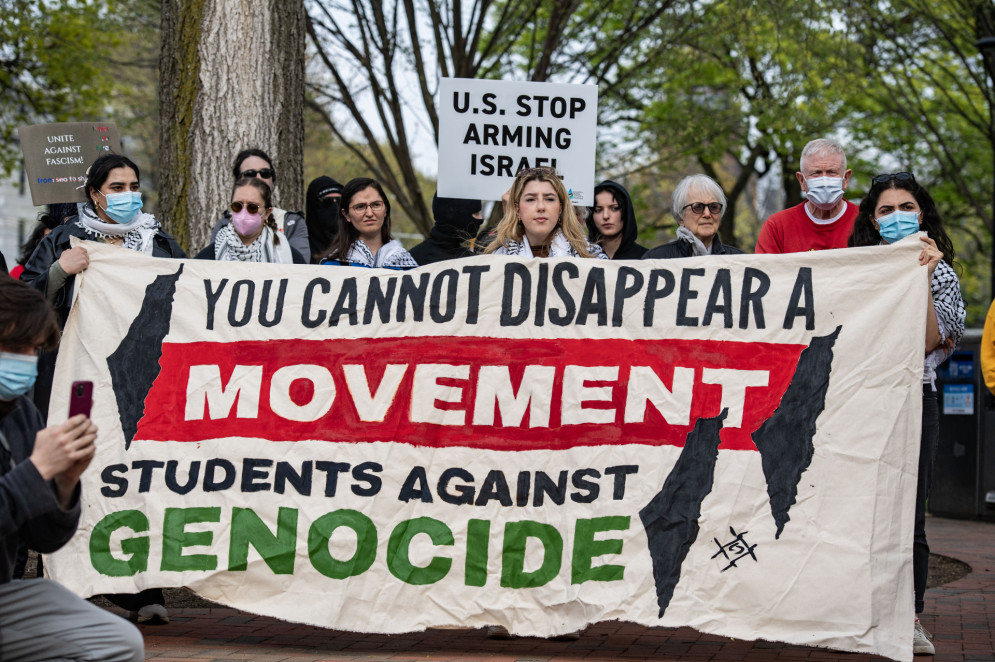 ParaTodosVerem: A imagem mostra um grupo de estudantes em um protesto em Harvard. Eles estão segurando uma faixa onde se lê "Você não pode parar um movimento - estudantes contra o genocídio". Ao fundo, outras pessoas seguram cartazes, incluindo um que diz "EUA pare de armar Israel". Os manifestantes estão em um ambiente ao ar livre, com árvores ao fundo(Foto: Joseph Prezioso / AFP)