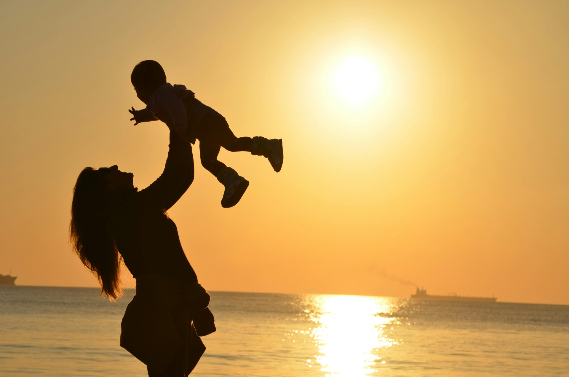 ParaTodosVerem: uma mulher levantando um bebê. Os dois estão na praia (Foto: Pexels/Pixabay)