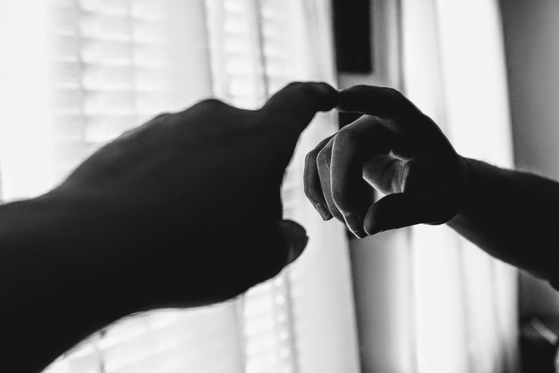 ParaTodosVerem: imagem em preto e branco mostra uma mão estendida em direção a um espelho. No reflexo, a mesma mão parece se aproximar da original, como se fossem tocar uma à outra. Ao fundo, entra uma luz suave por entre cortinas, iluminando parte da cena (Foto: Pexels/Jenna Hamra)
