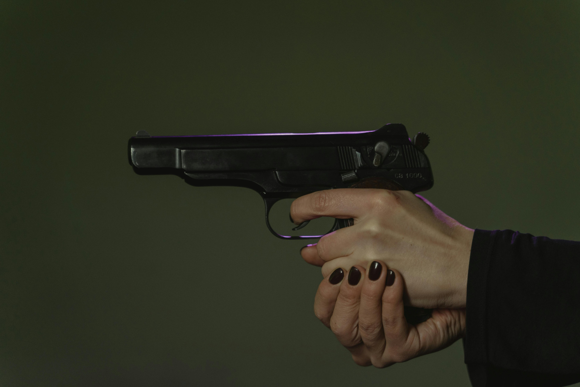 Imagem ilustrativa de apoio. ParaTodosVerem: uma mão segura uma pistola preta com firmeza, os dedos posicionados sobre o gatilho e a empunhadura. O fundo é neutro e escuro, destacando o objeto em foco (Foto: Pexels/Tima Miroshnichenko)