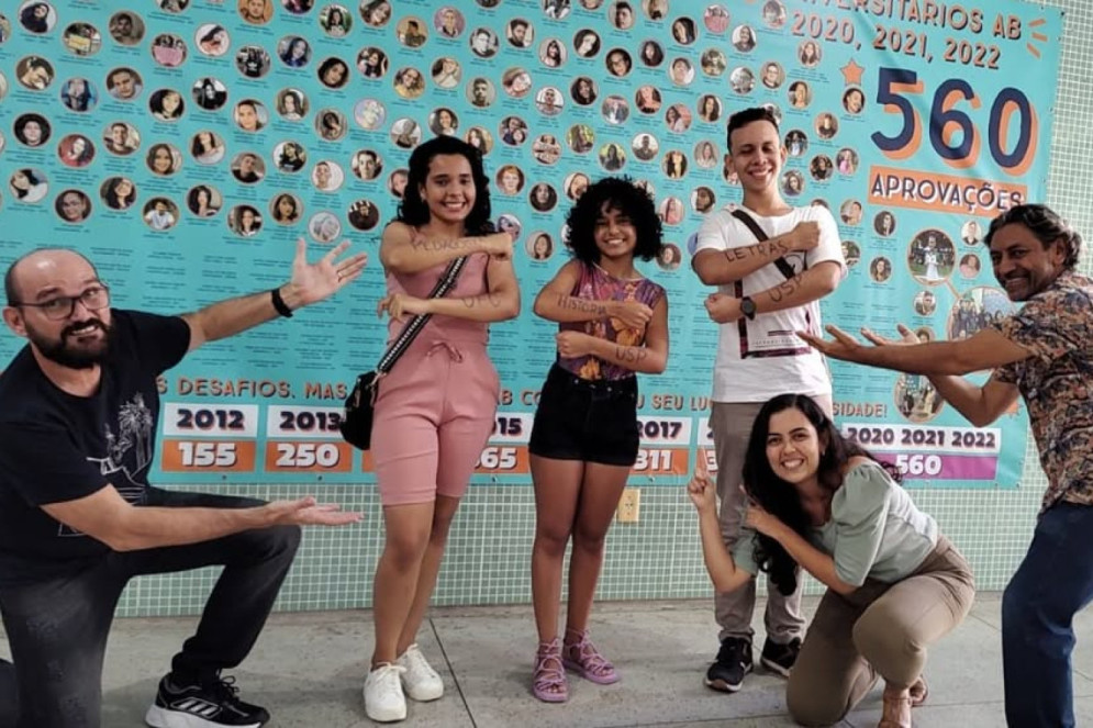 Otacílio e professores em frente ao painel de aprovados comemorando a aprovação de três estudantes(Foto: Reprodução/ Instagram @abescolaoficial)