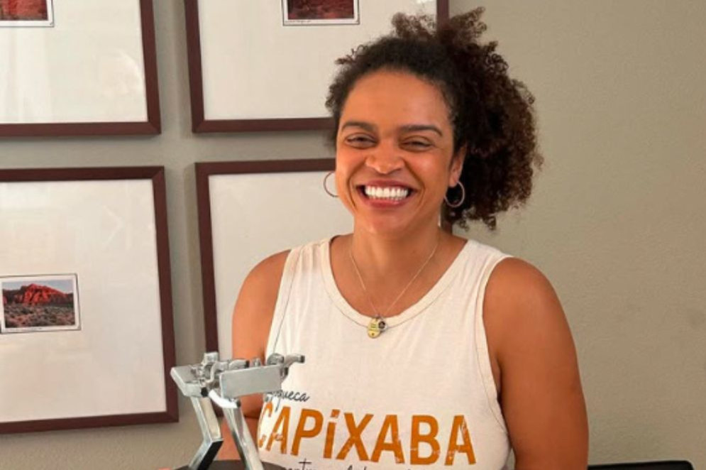 Barbara Marques é brasileira, cineasta e vive nos EUA desde 2018. Ela é uma mulher negra de cabelo crespo escuro e na imagem sorri enquanto segura um troféu(Foto: Reprodução/ Instagram @barbaramarianamarques)