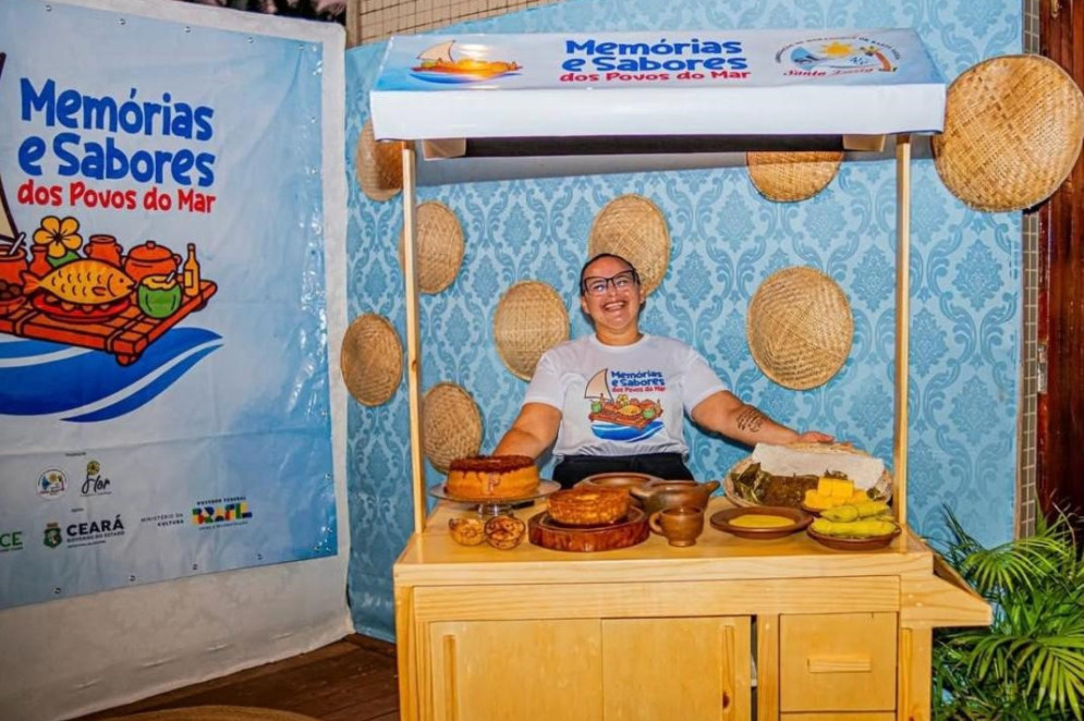 Uma das integrantes do projeto Memórias e Sabores dos Povos do Mar, com o Carrinho da Cultura Alimentar, no dia de lançamento do produto(Foto: Arquivo pessoal/Asmosal)