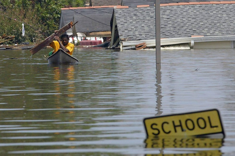 ParaTodosVerem: Um morador usa uma prancha para remar pelas águas da enchente em Nova Orleans, em agosto de 2005.(Foto: James Nielsen / AFP)