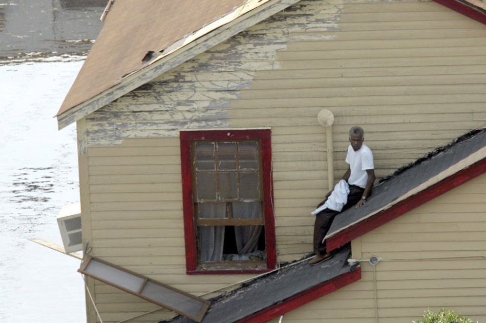 ParaTodosVerem: Um homem espera para ser resgatado de um telhado enquanto as águas da enchente continuam a subir, em 2 de setembro de 2005, em Nova Orleans.(Foto: Robert Galbraith / AFP)