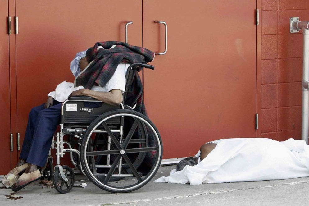 Os corpos de duas vítimas do furacão permanecem em uma porta do ginásio esportivo Superdome, em Nova Orleans, no dia 2 de setembro de 2005 (Foto: James Sullivan / AFP)